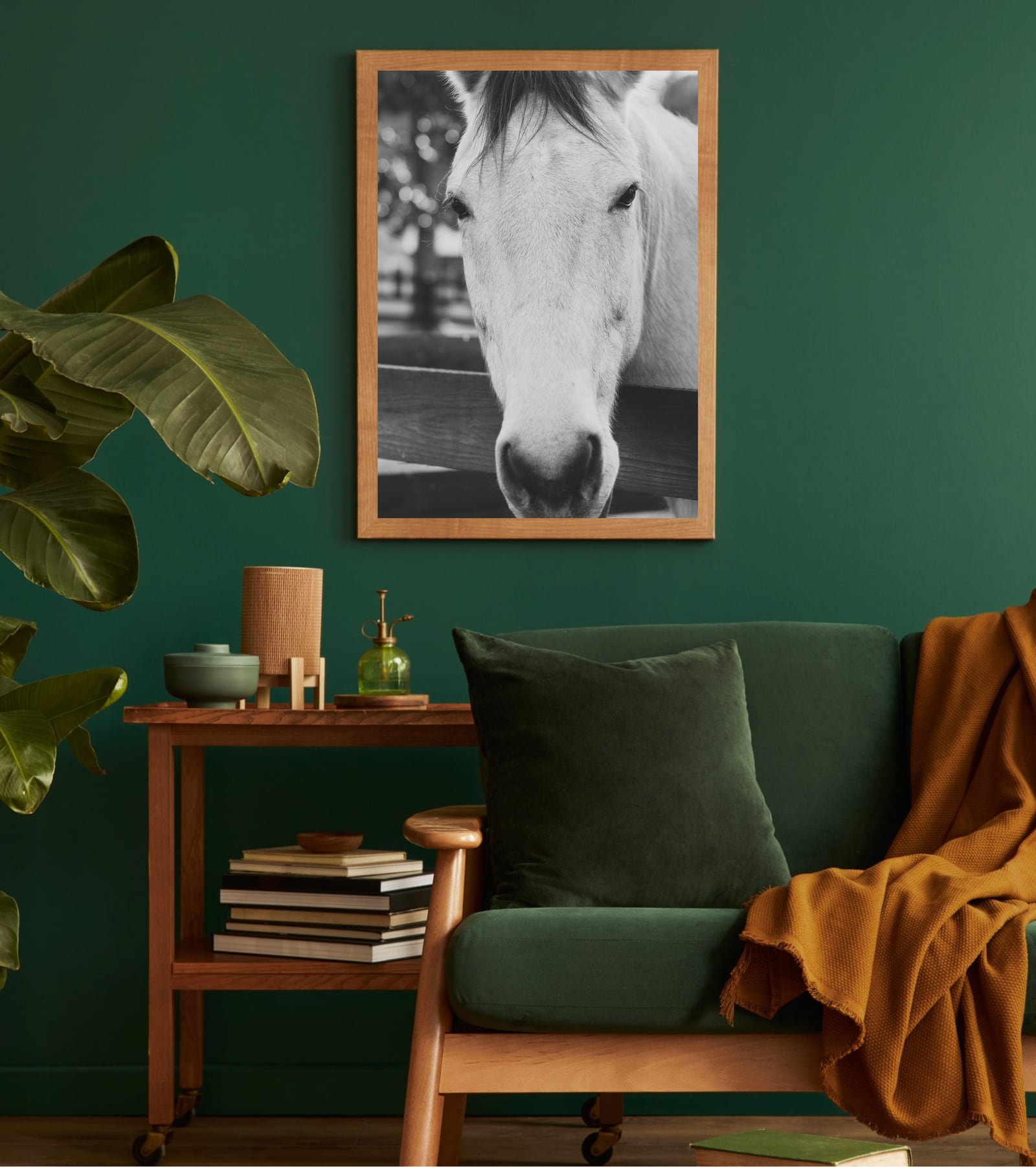 A framed horse portrait above a green armchair in a deep green study