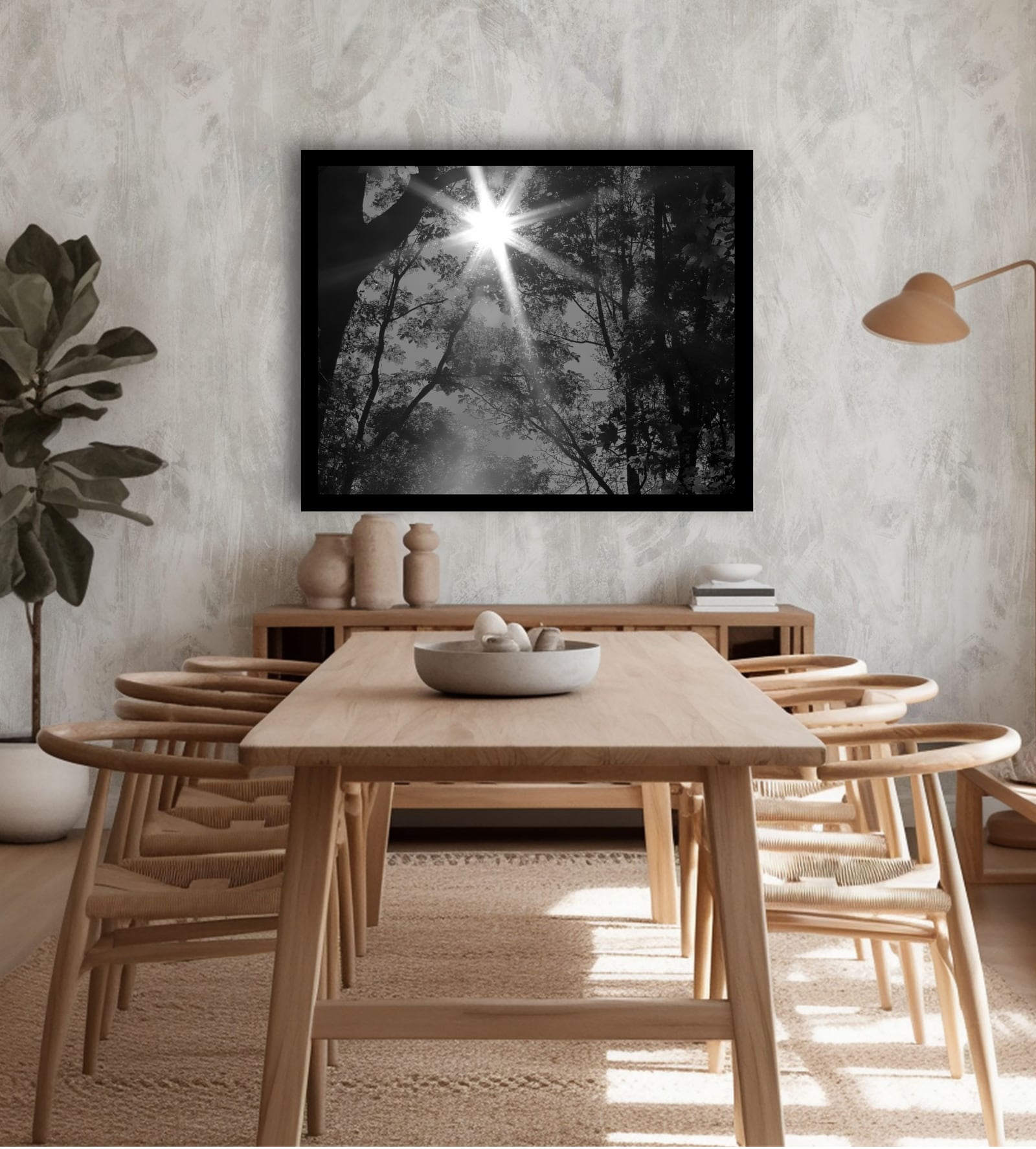 A framed black and white tree photograph above a wooden dining table
