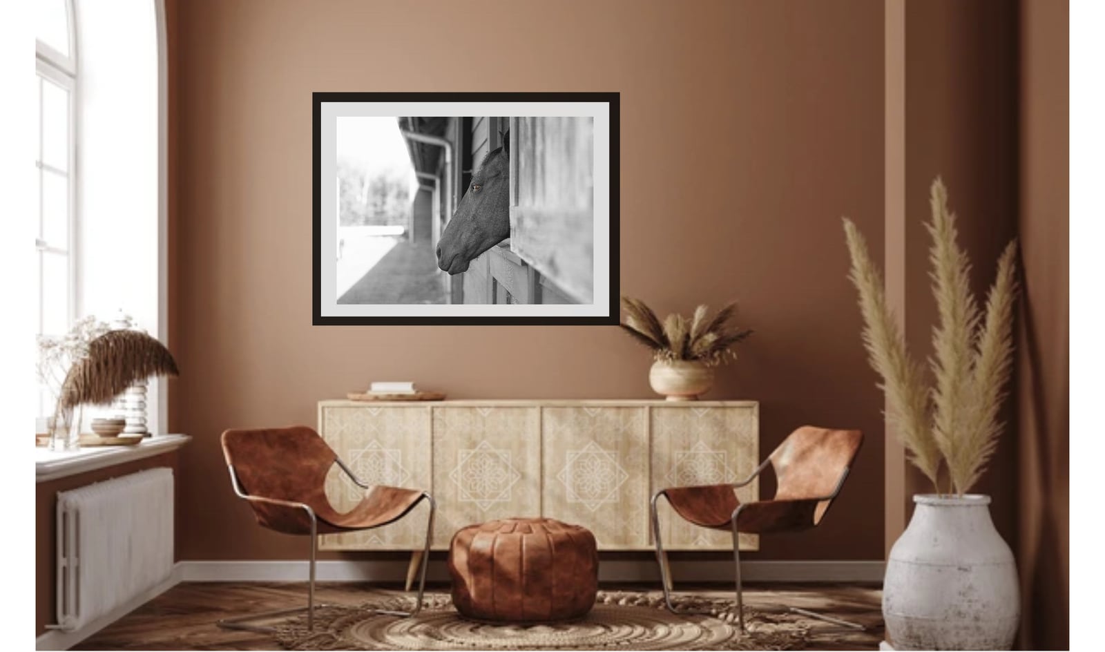 A framed black and white architectural photograph above a sideboard in a terracotta room