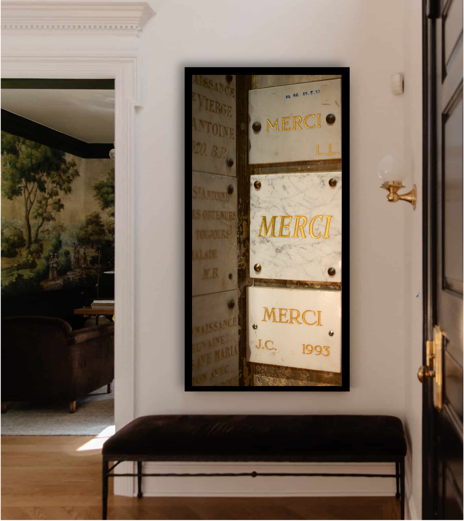 A tall framed photograph carrying the word Merci beside a hallway bench