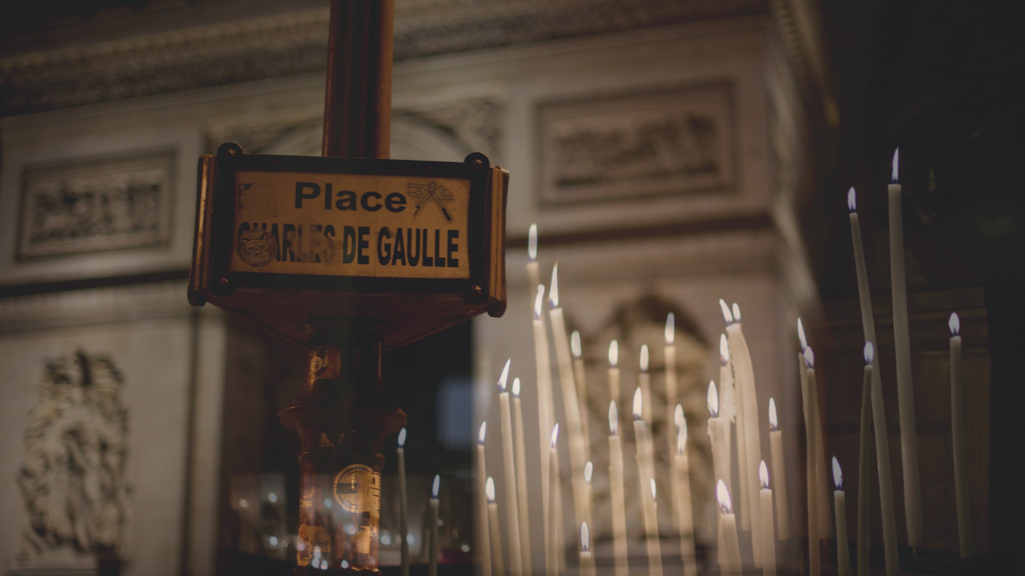 A Place Charles de Gaulle street sign layered over a bank of votive candles, Paris